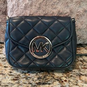 A Michael Kors small black and gold purse.